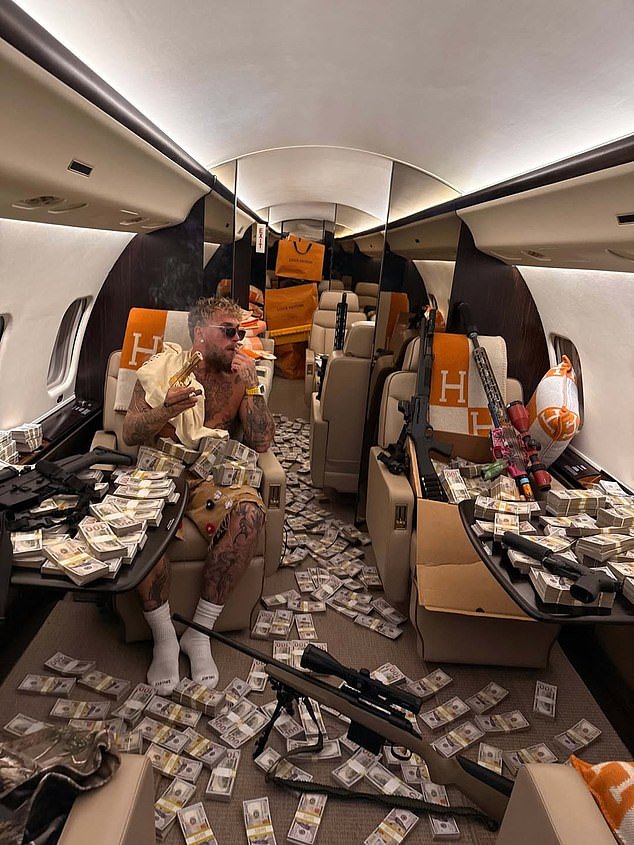 ¿Vale la pena romperte la mandíbula, Jake? Paul, con cicatrices de batalla, muestra sus ganancias de la derrota por nocaut de £ 140 millones ante Anthony Joshua, posando con fajos de billetes y SEIS armas en un jet privado.