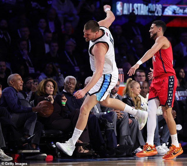 Obama atrapa un balón suelto mientras está sentado en la cancha con Michelle en el Juego de Estrellas de la NBA