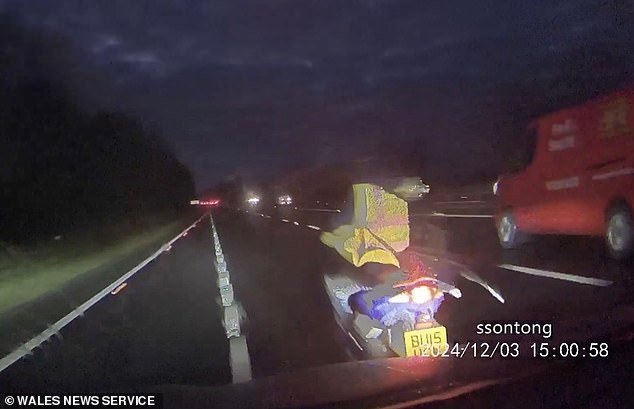 En ese momento, la profesora, que se apresura a ir a la escuela, empuja a un conductor de ciclomotor con visera fuera de su bicicleta mientras es captada por su propia cámara.