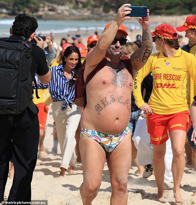¡Solo en Australia! Un local de Bondi vestido solo con contrabandistas de periquitos abraza al Príncipe Harry en la famosa playa de Sydney